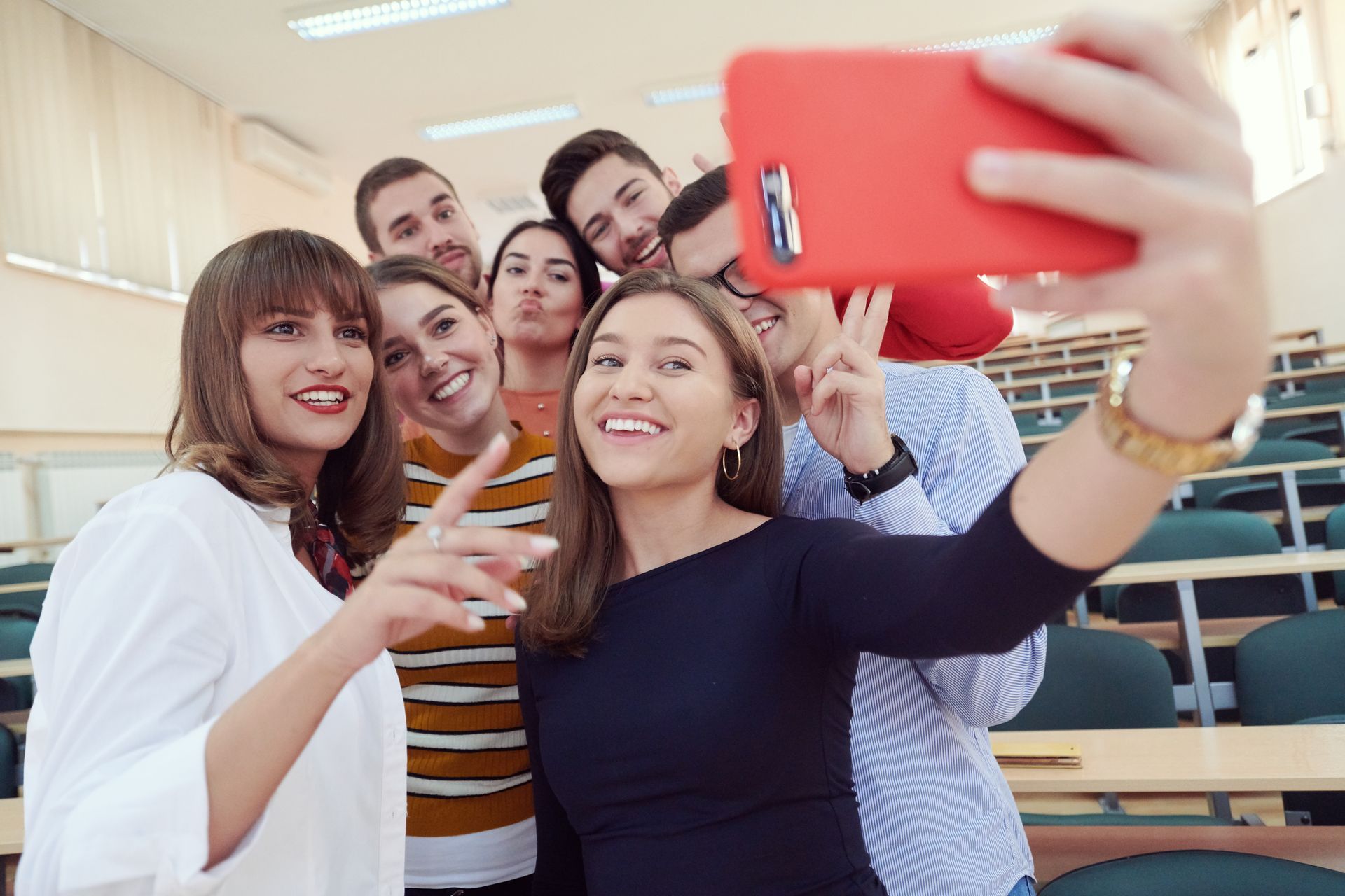 A group of young people are taking a selfie in a classroom.
