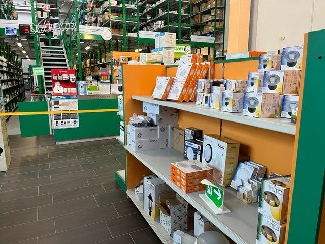 Scaffali che espongono componenti elettrici confezionati in un negozio. Dettagli verdi e arancioni ovunque.