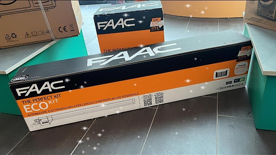 Scatola del kit FAAC ECO su un pavimento, con una scatola FAAC più piccola dietro. Confezione nera e arancione.