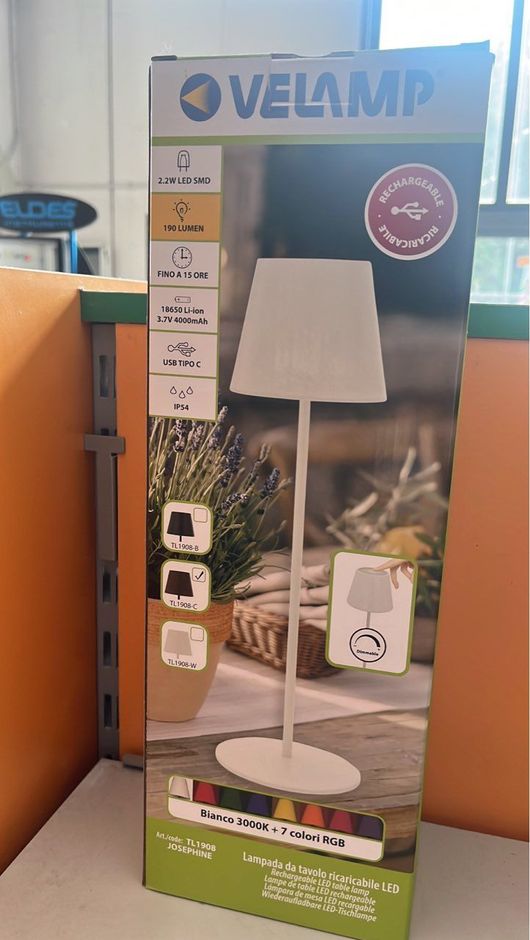 Scatola per lampada da tavolo Velamp bianca, raffigurante la lampada su un patio. Dotata di base che cambia colore.