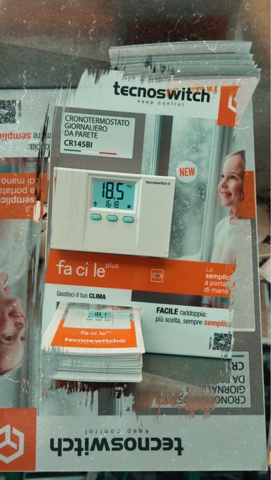 Display del termostato Tecnoswitch con una persona sorridente sullo sfondo, impostato a 18,5 gradi.