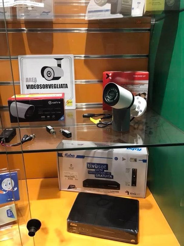 Telecamere e attrezzature di sicurezza esposte all'interno di una teca di vetro in un negozio.