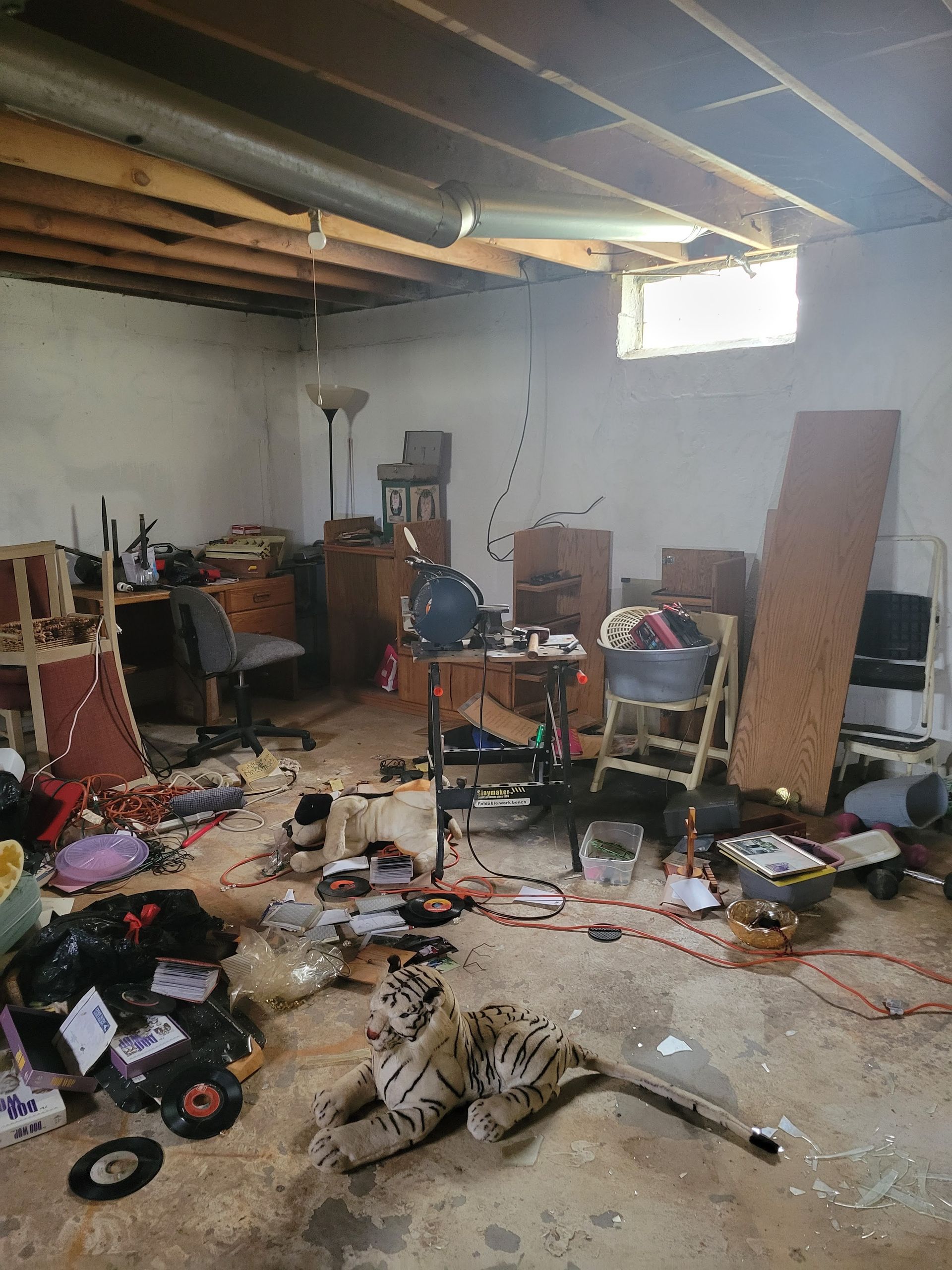 A messy room with a lot of furniture and records on the floor.