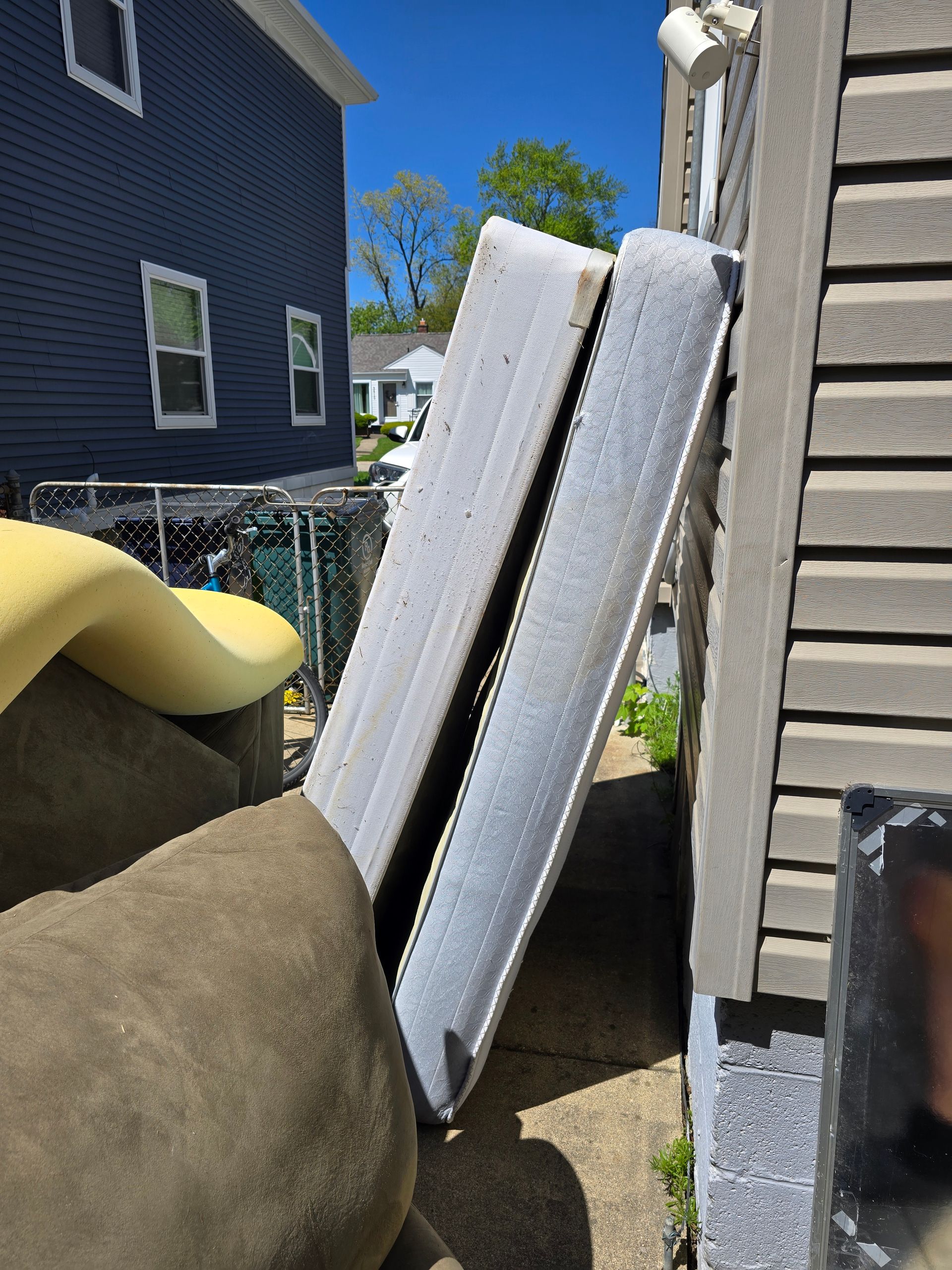 A mattress is leaning against a wall next to a house.
