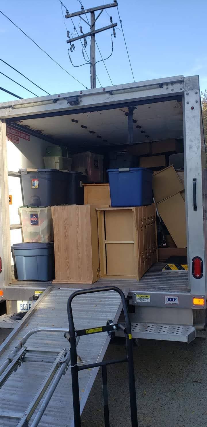 A moving truck is filled with boxes and furniture to be disposed of.