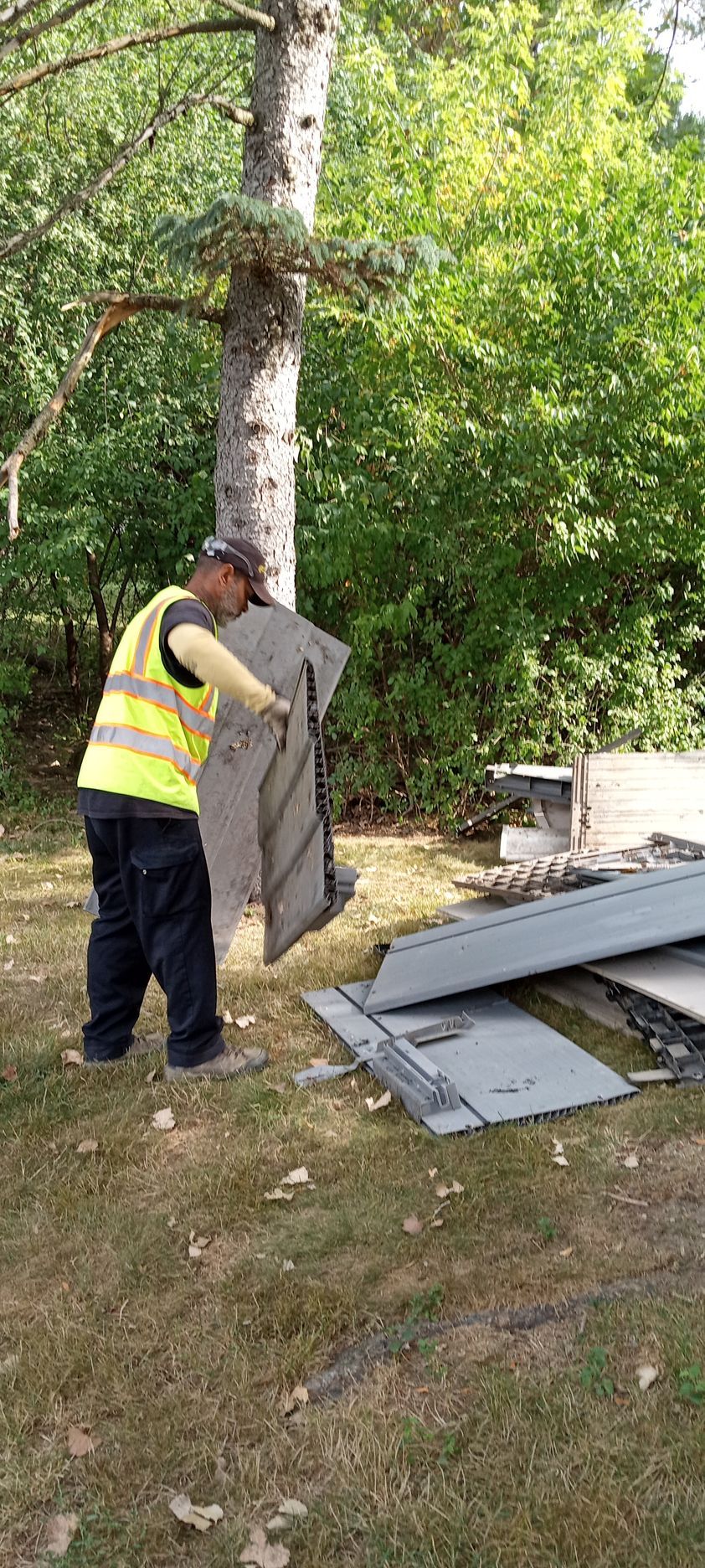 A man is standing in the grass holding a piece of wood.