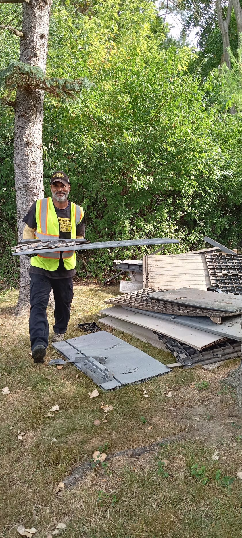 A man in a yellow vest is standing next to a pile of concrete.