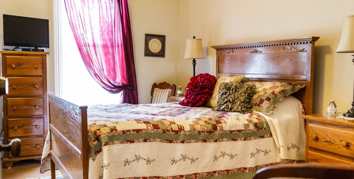 A bedroom with a bed , dresser , nightstand and television.