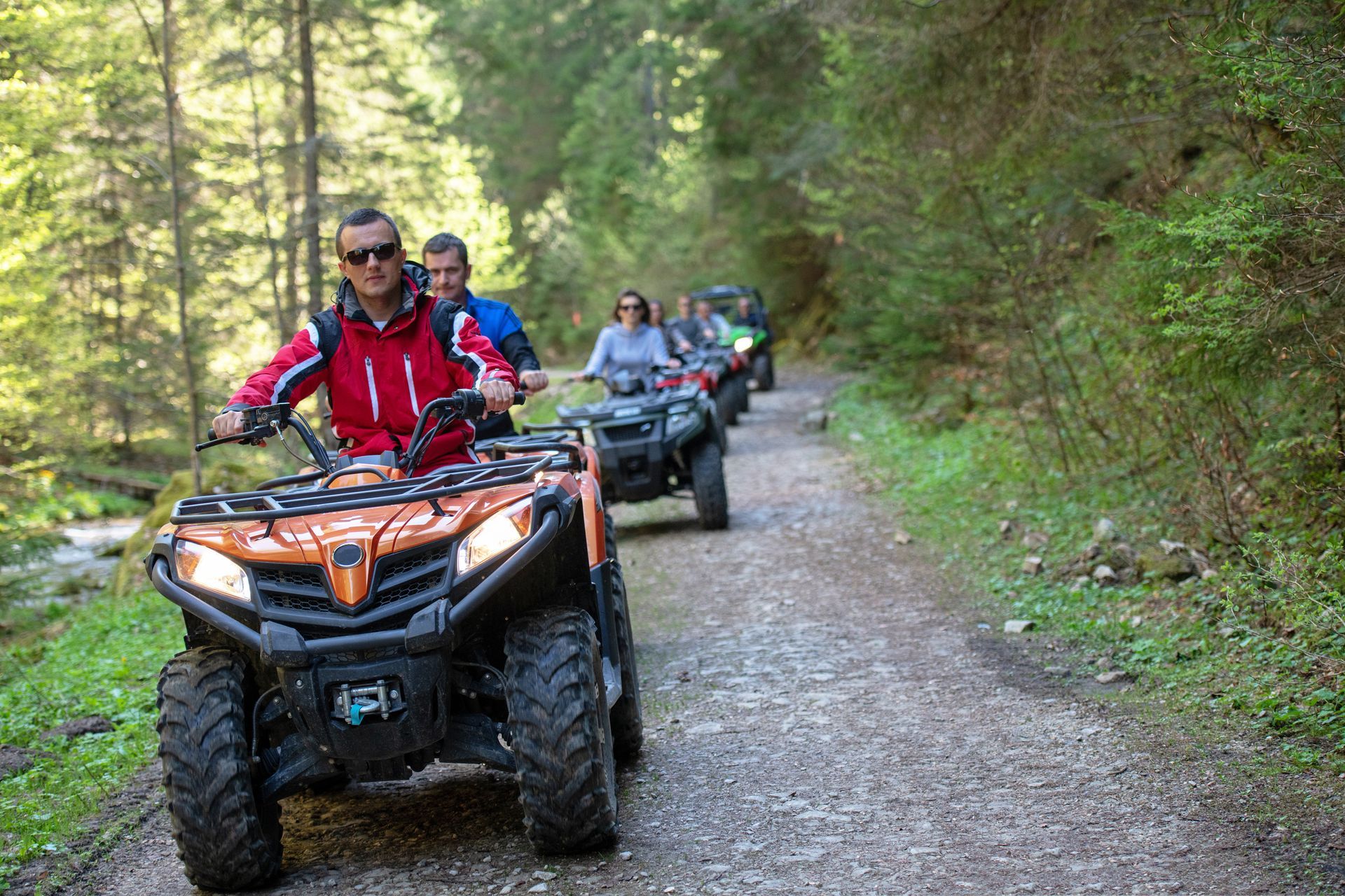 A group of people are riding atvs down a dirt road.