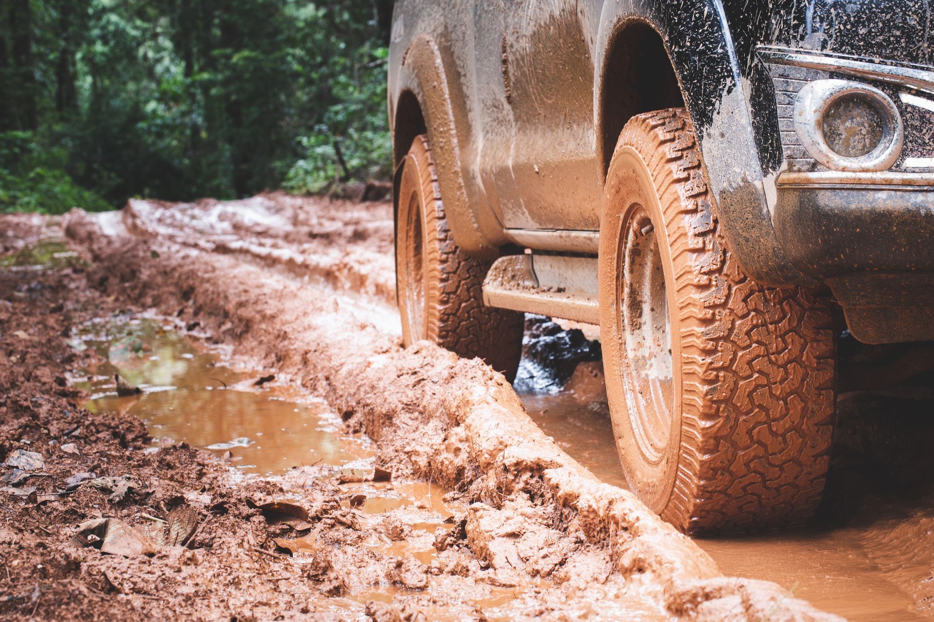 A muddy truck is driving down a muddy road.