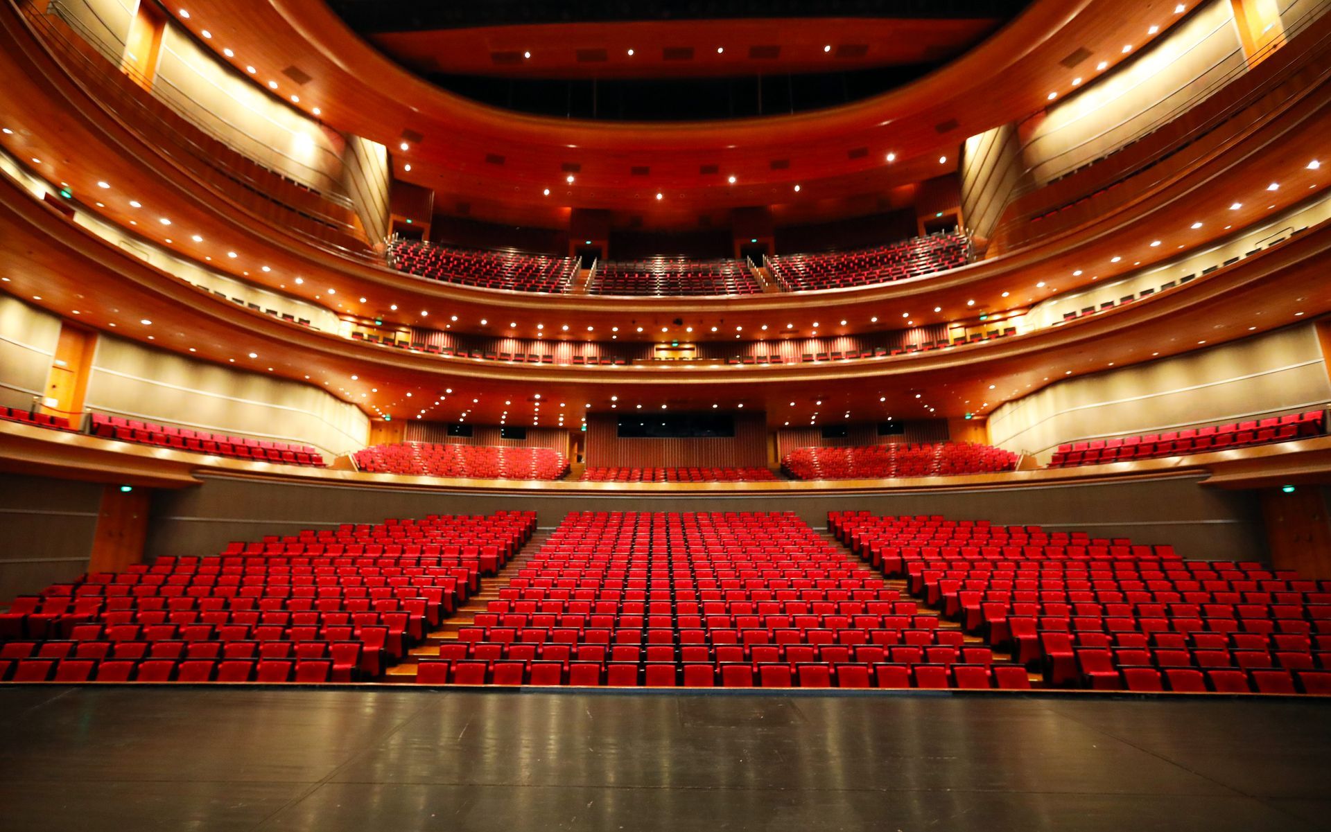 An empty auditorium with red seats and a stage