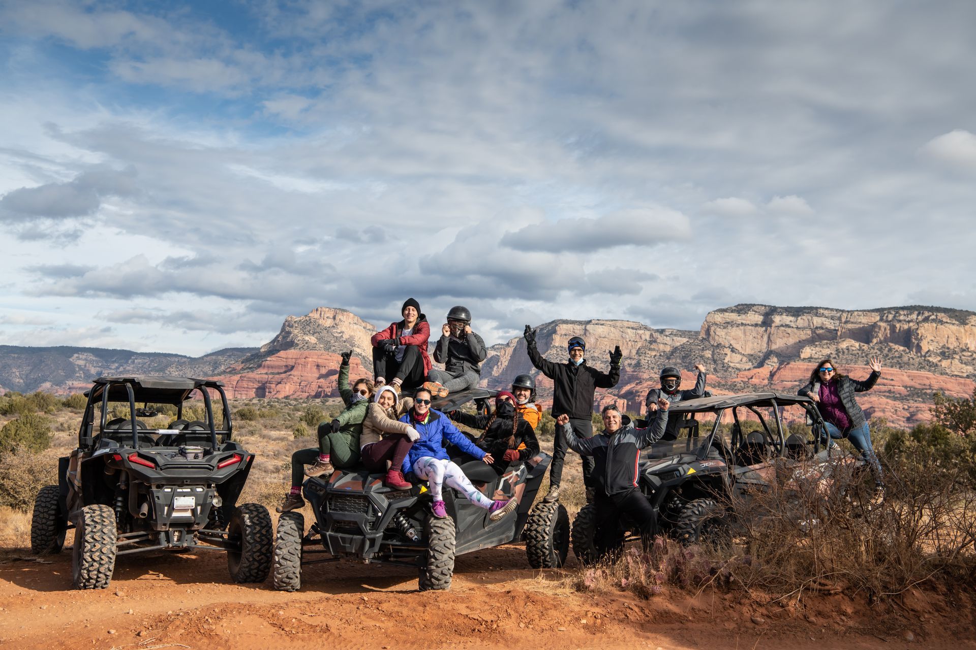 A group of people are posing for a picture while riding atvs in the desert.