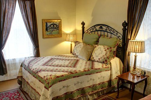 A bedroom with a bed , two lamps and a picture on the wall.