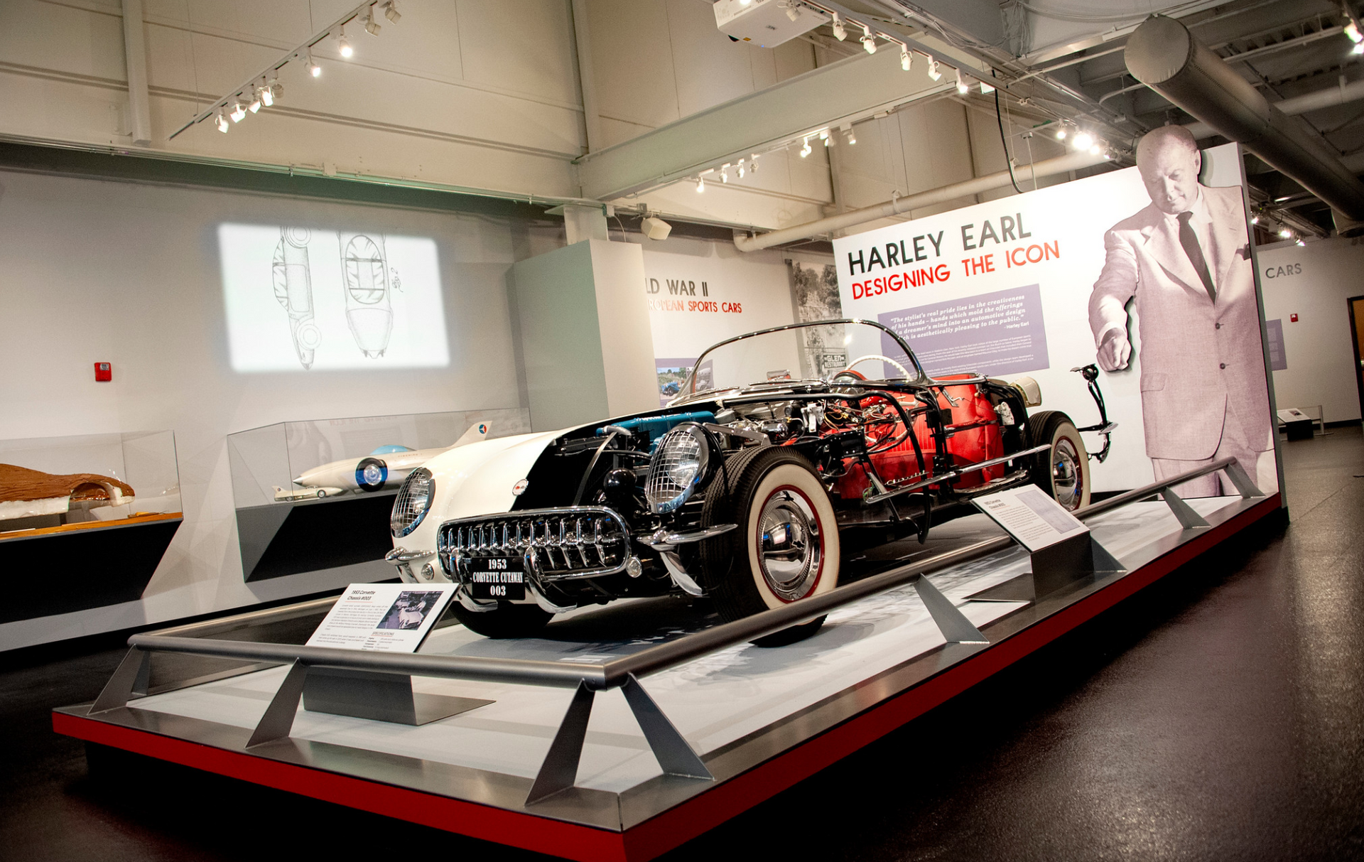 A car is on display in a museum with a picture of jimmy earl behind it