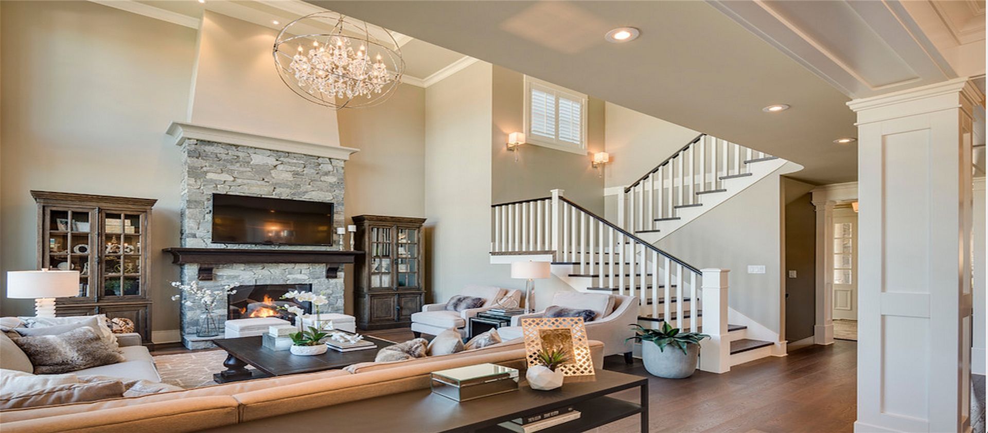 Elegant living room with chandelier, fireplace, built-in cabinets, and staircase.