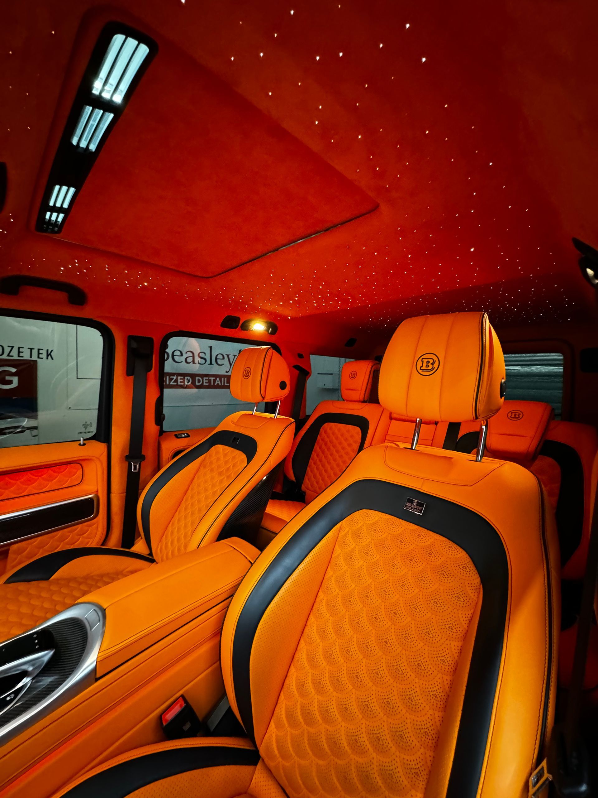 Orange luxury car interior with quilted seats and red ceiling lighting