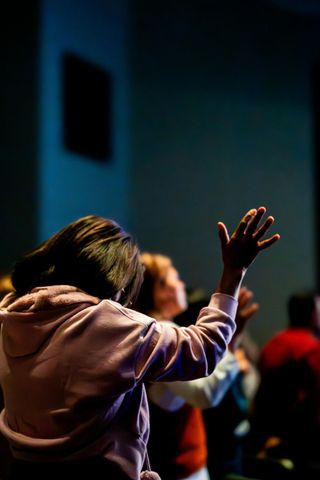 A group of people are raising their hands in the air in a dark room.