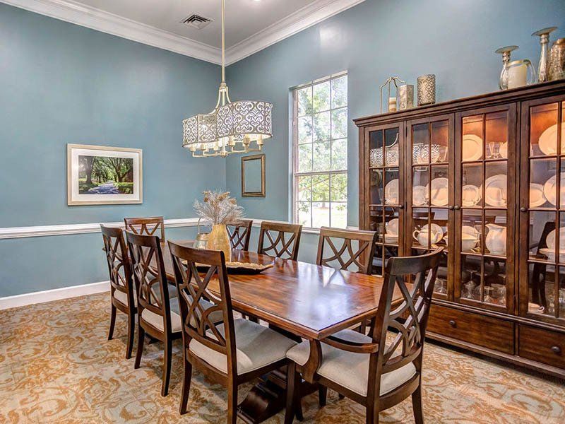 Formal dining room with wooden table and chairs, blue walls, a china cabinet, and chandelier.