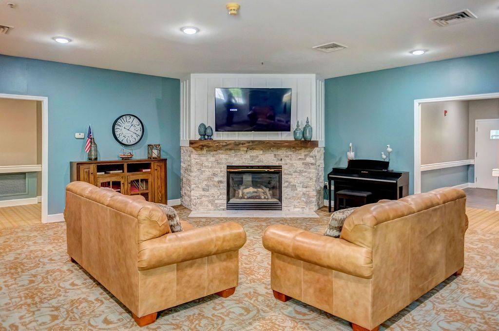 Cozy living room with fireplace, two brown leather chairs, piano, and light blue walls.