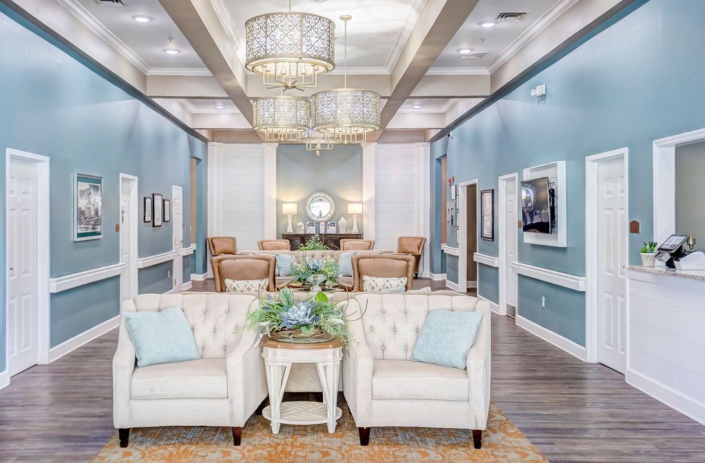 Elegant waiting room with blue walls, chandeliers, seating, and decorative accents.