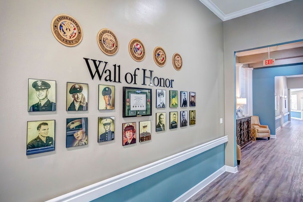 Wall of Honor with portraits and seals, hallway with wood floors and teal accent.
