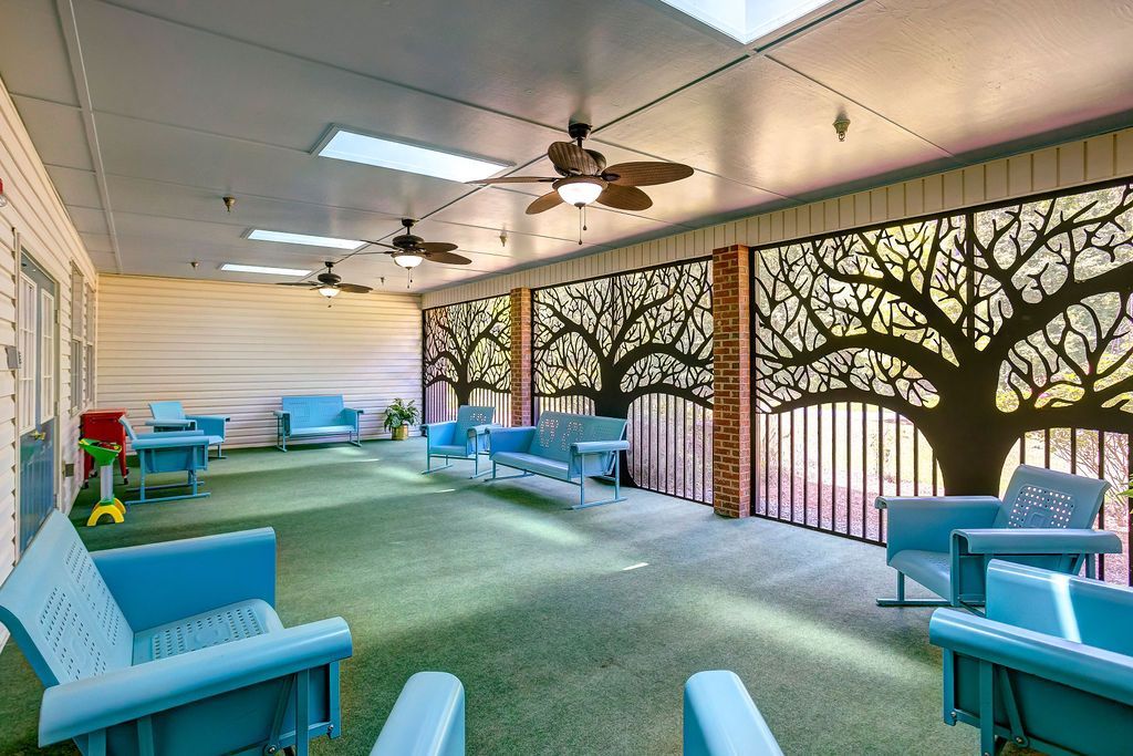 Covered outdoor patio with light blue furniture, artificial turf, and tree-shaped cutouts.