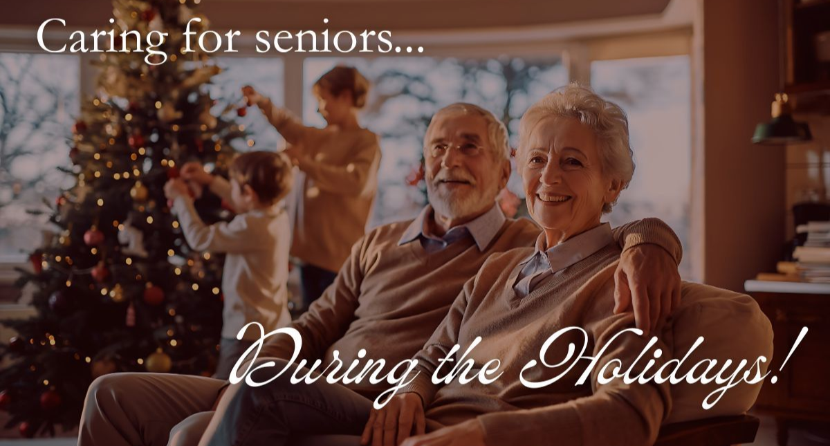 Elderly couple smiles on a couch with family decorating a Christmas tree in the background. 