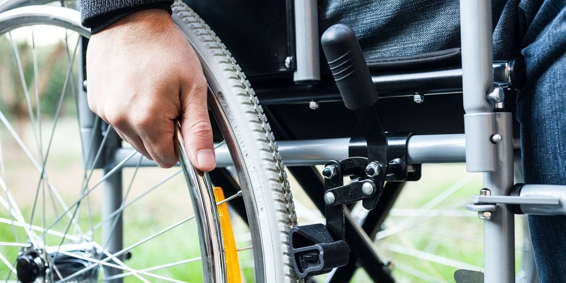 A person in a wheelchair is adjusting the wheel.