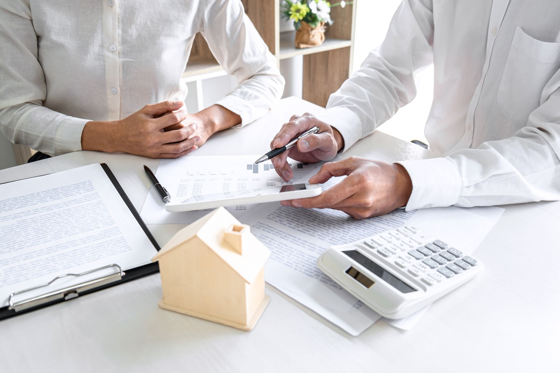 A man and a woman are sitting at a table looking at papers and a calculator.