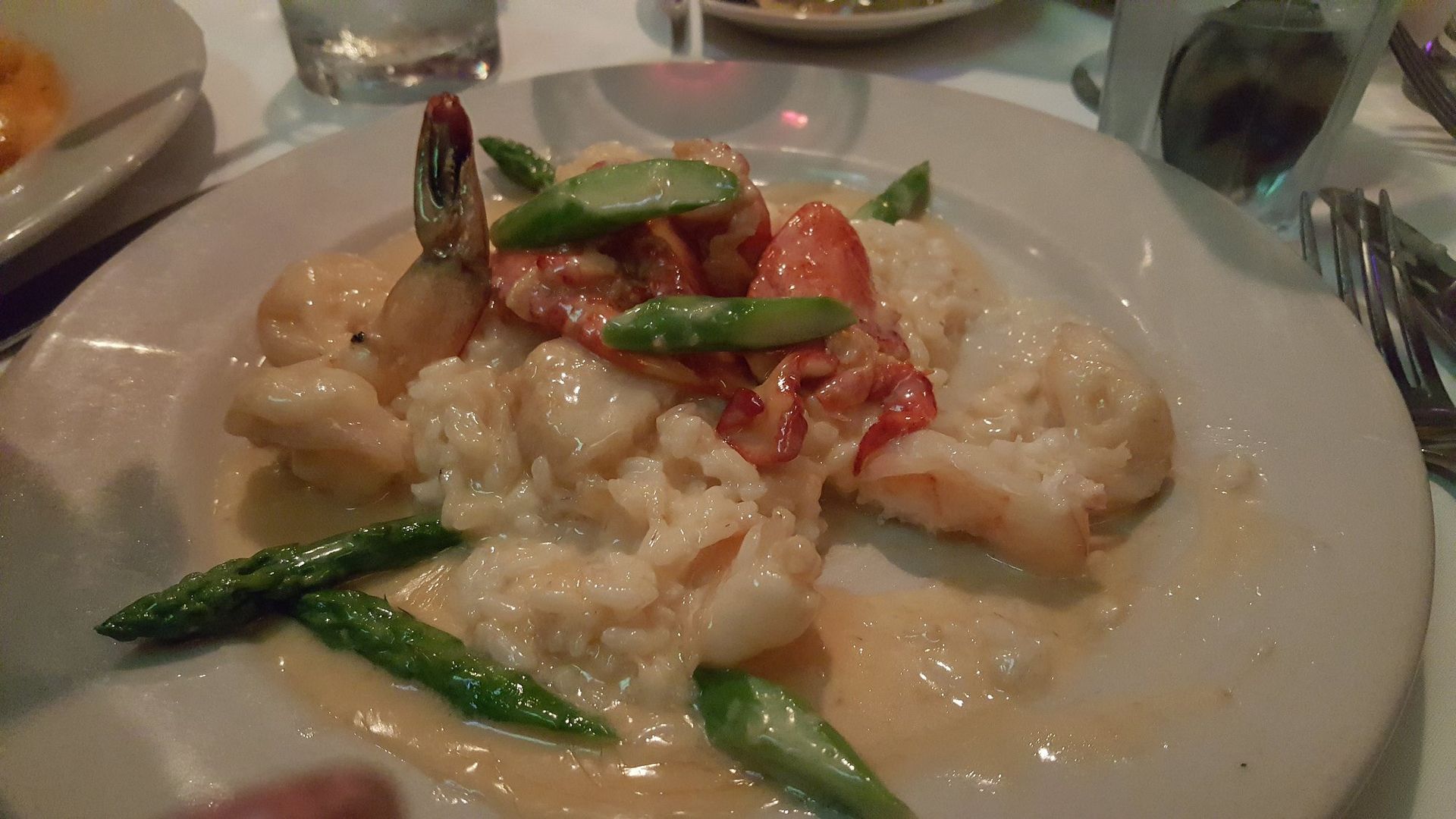 A plate of food with shrimp and asparagus on a table.