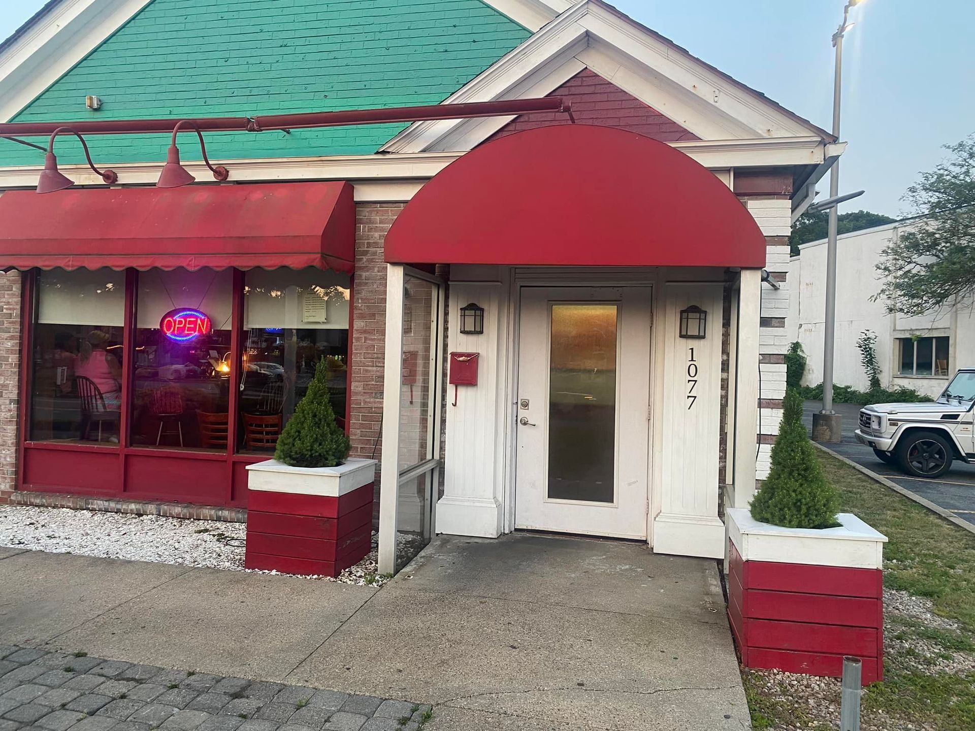 A restaurant with a red awning and a green roof