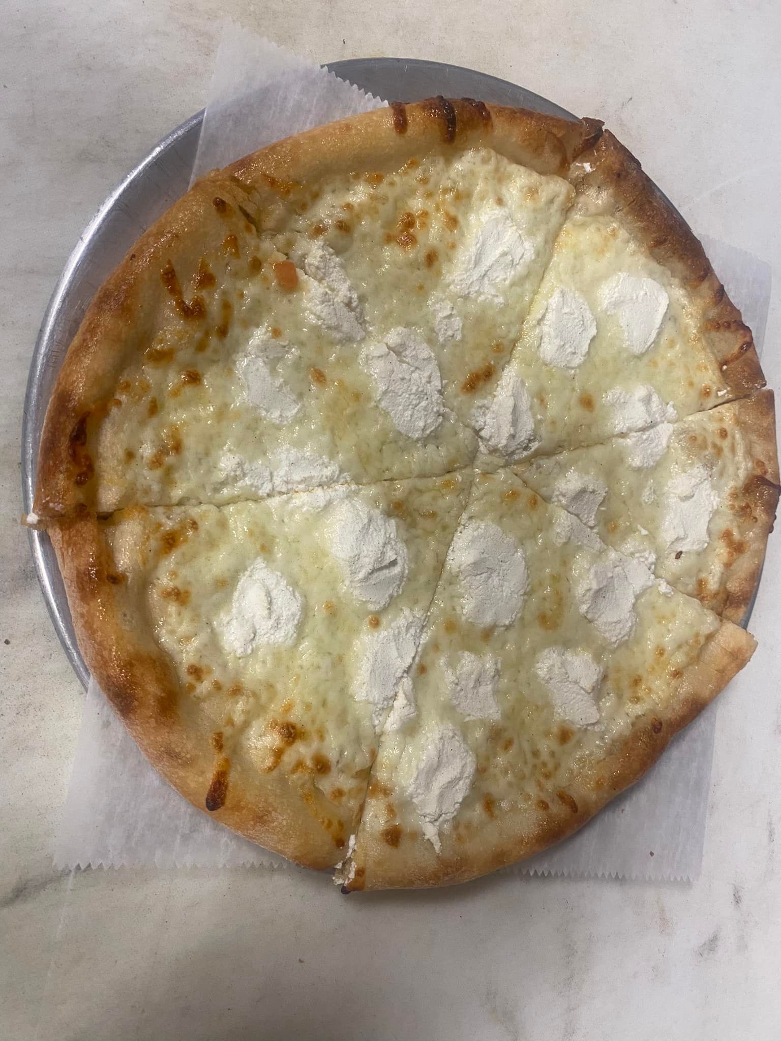 A white pizza with a lot of cheese on it is on a pizza pan.