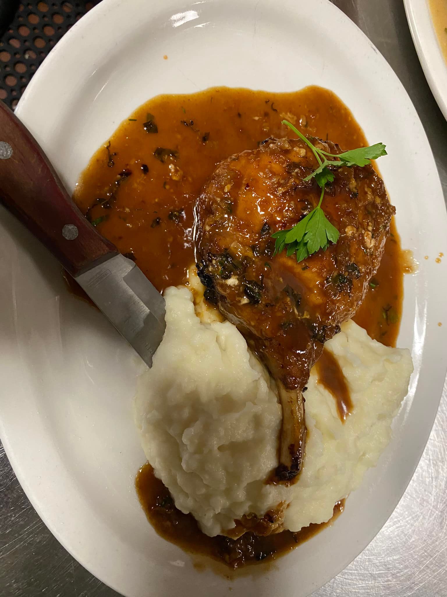 A white plate topped with mashed potatoes , meat and sauce.