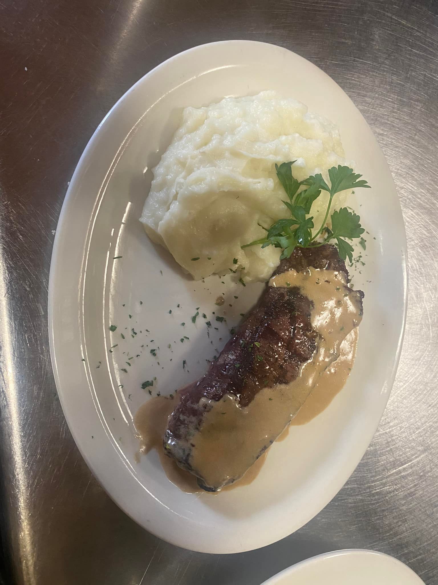 A white plate topped with meat and mashed potatoes