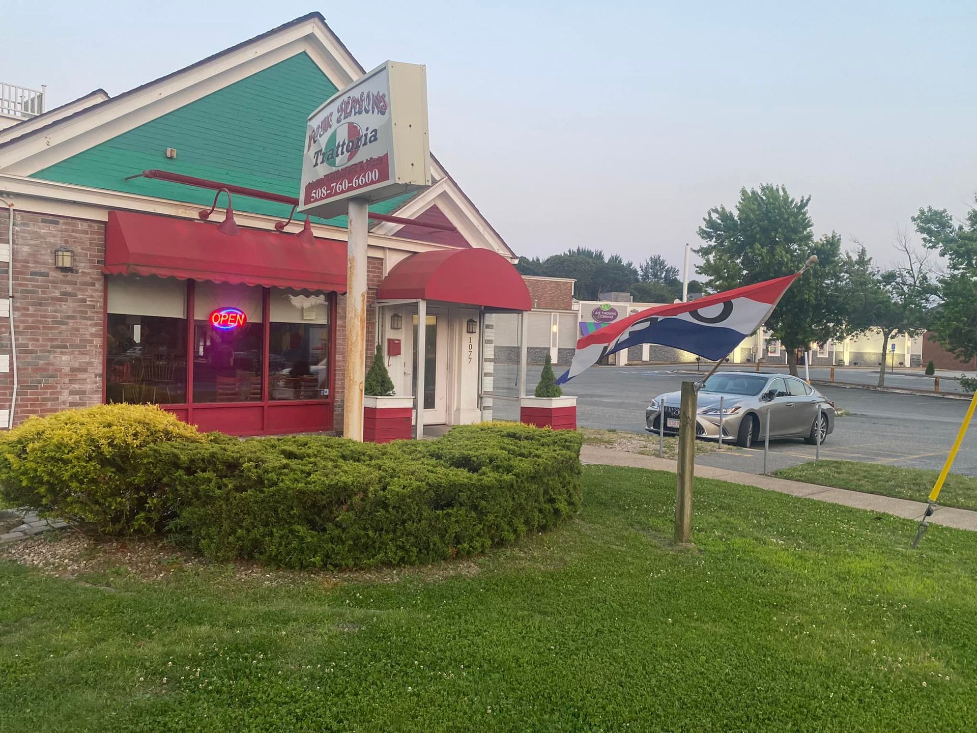 A car is parked in front of a restaurant with a red awning.