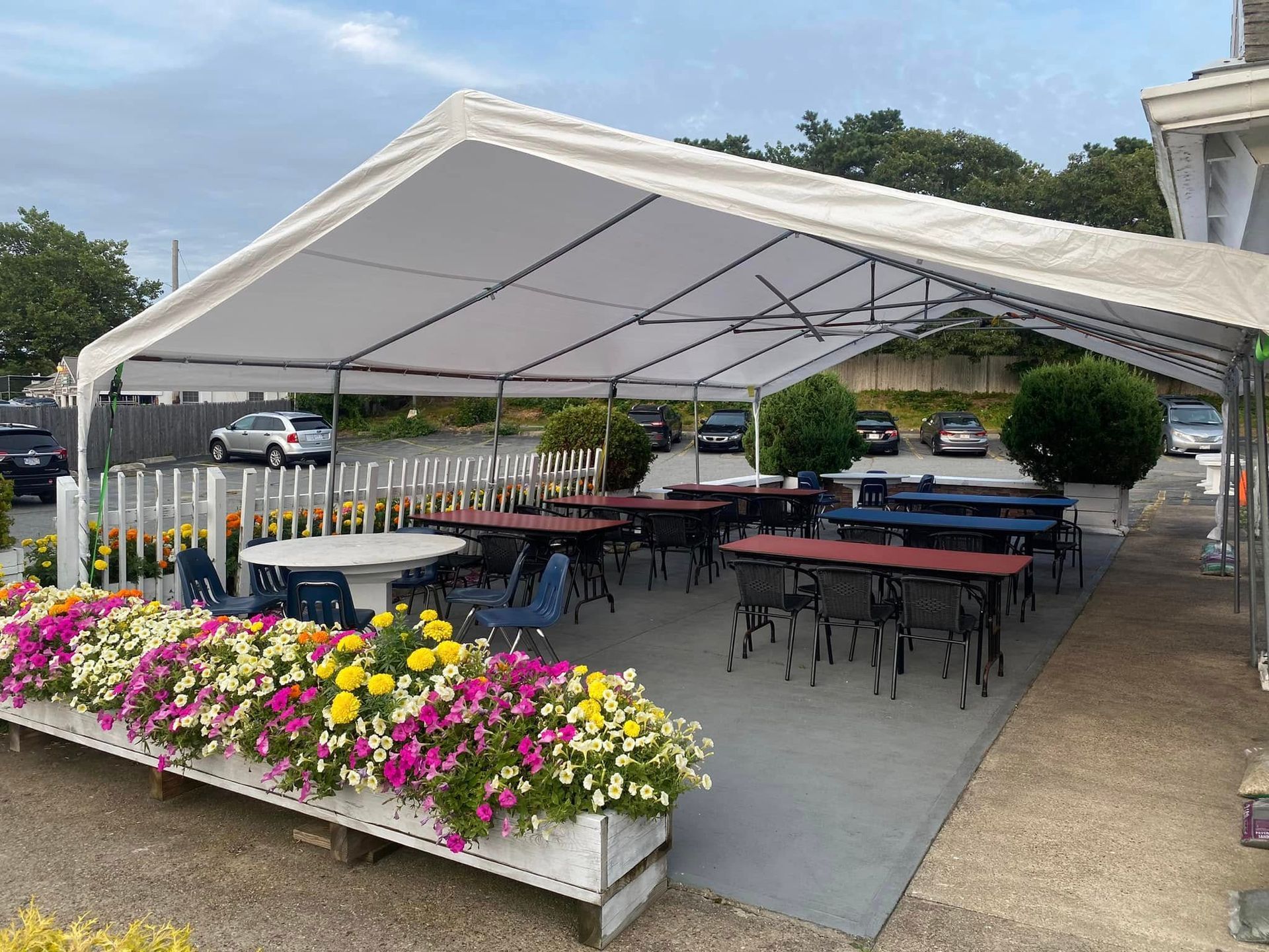 A large white tent with tables and chairs underneath it.