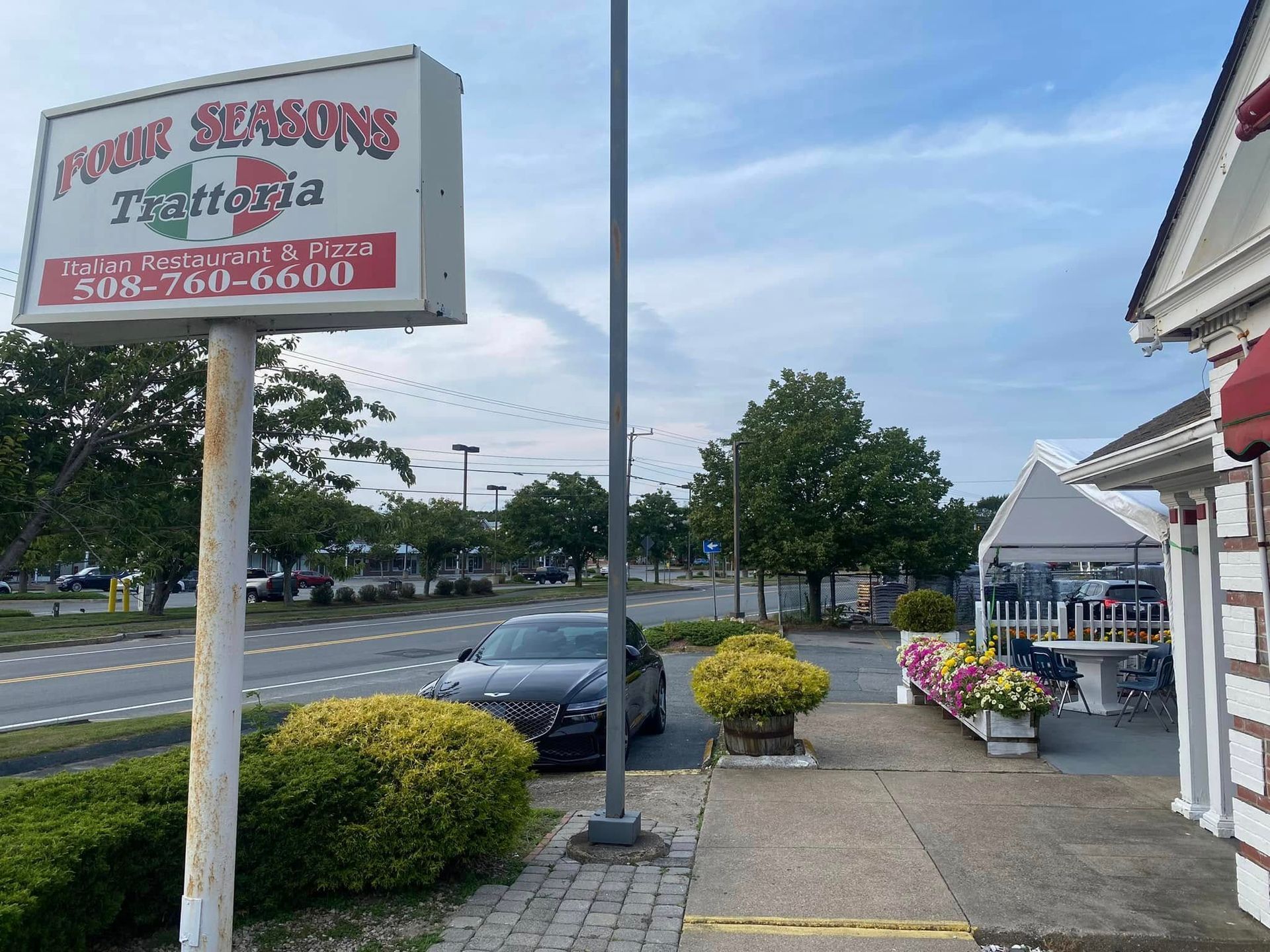 A car is parked in front of a sign for four seasons trattoria
