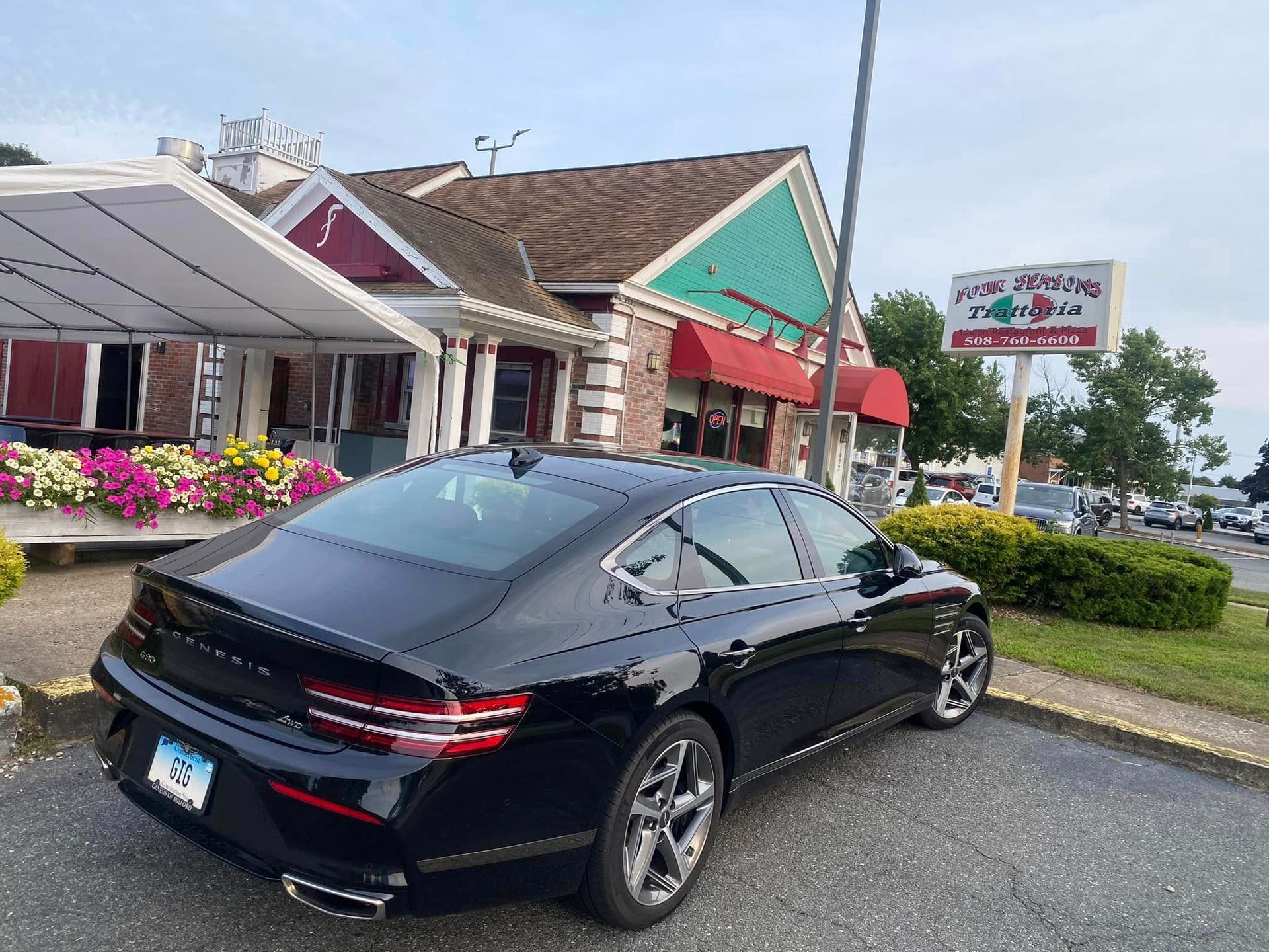 A black car is parked in front of a restaurant.