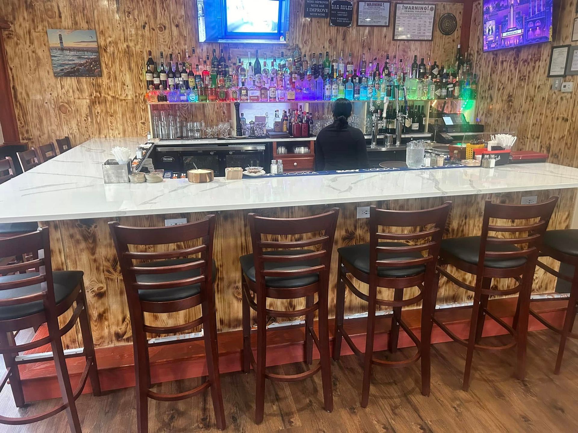 A man is standing behind a bar in a restaurant.