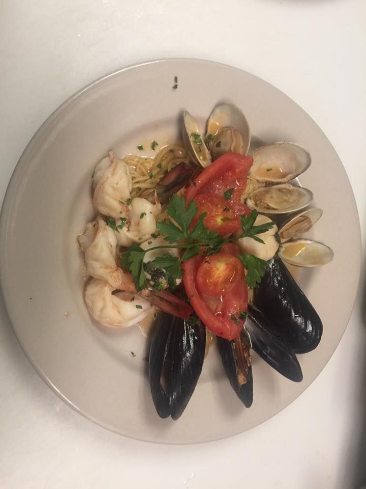 A white plate topped with shrimp mussels and tomatoes