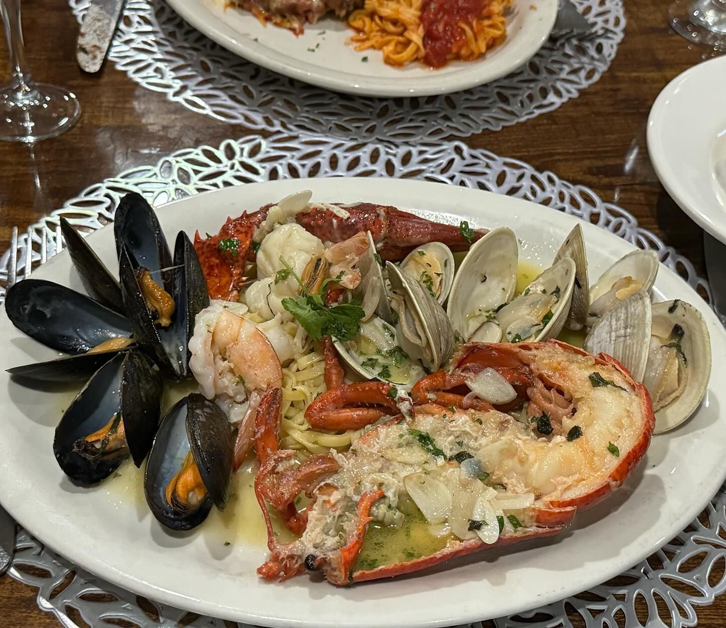 A plate of seafood including lobster , mussels , shrimp and clams on a table.