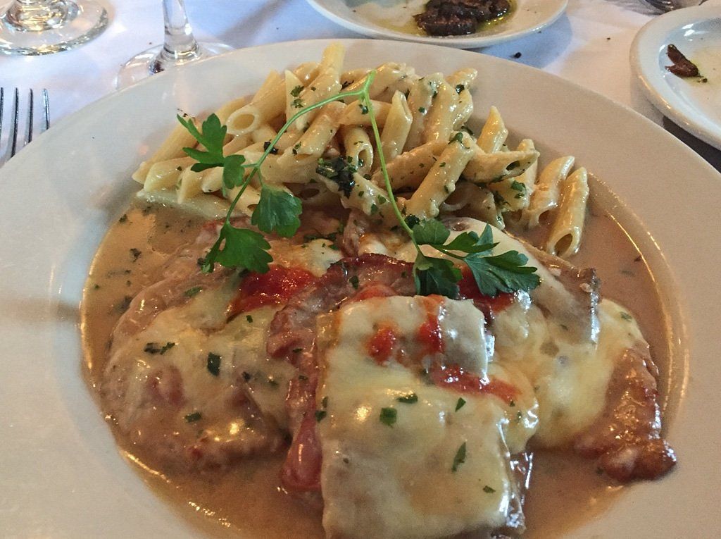 A white plate topped with meat and pasta on a table.