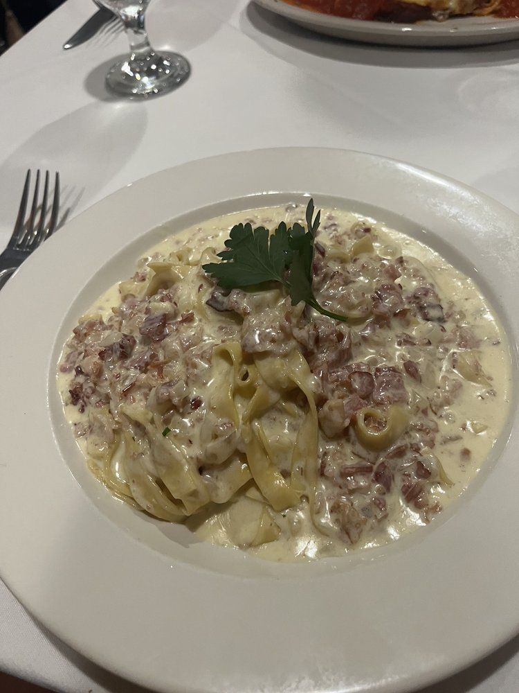 A white plate topped with pasta and sauce on a table.