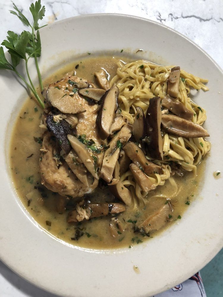 A bowl of soup with noodles and mushrooms on a table.