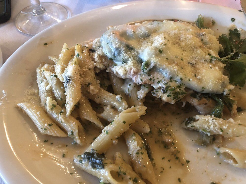 A white plate topped with pasta and a piece of meat