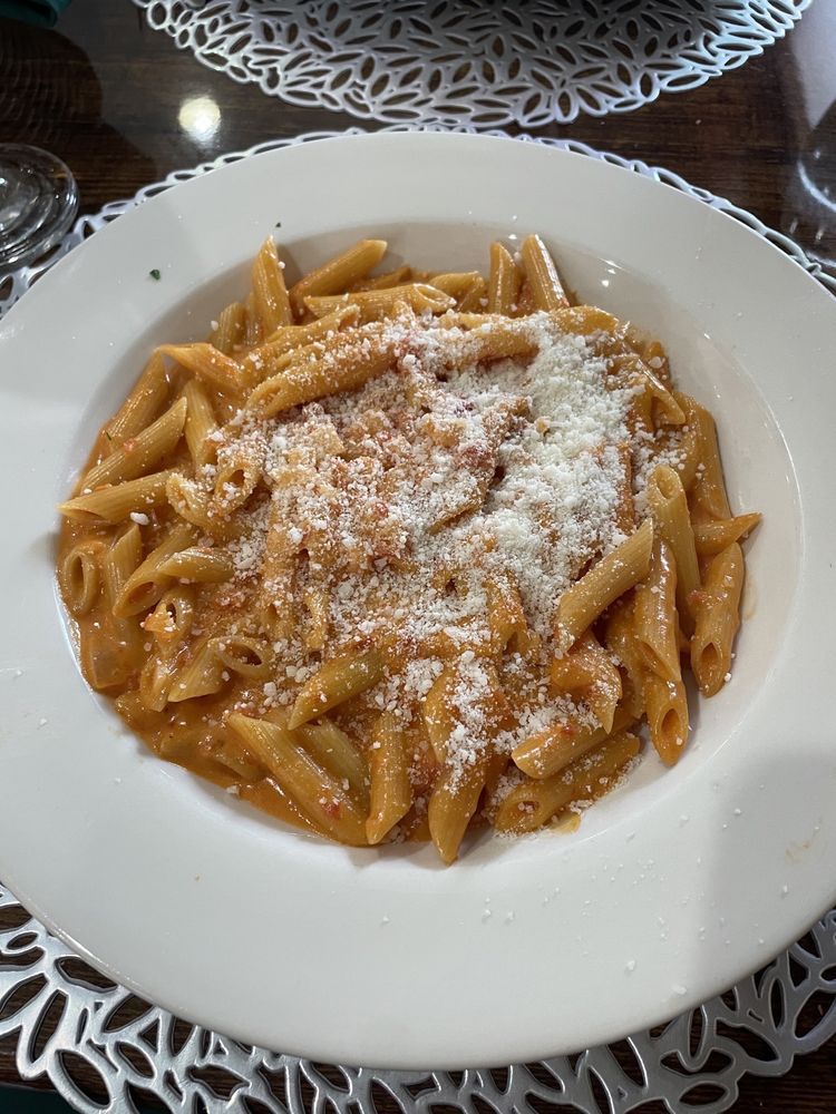 A white plate topped with pasta and cheese on a table.