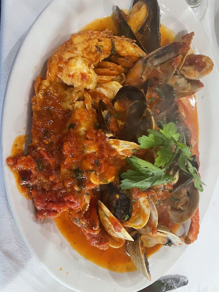 A white plate topped with seafood and sauce on a table.
