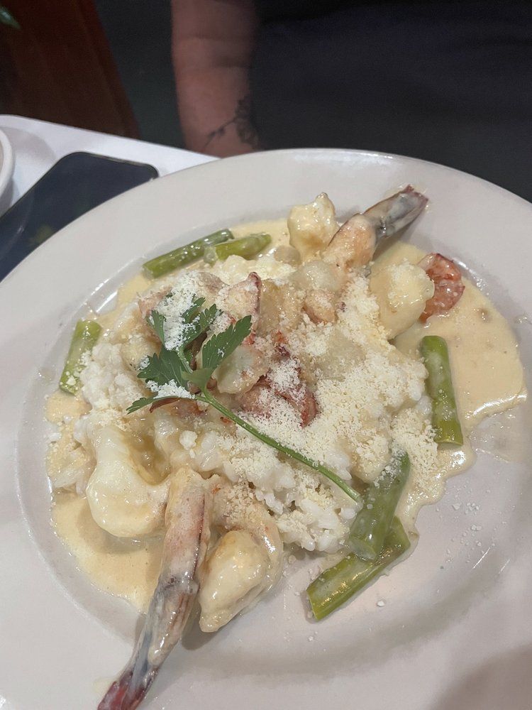 A close up of a plate of food with shrimp and asparagus on a table.