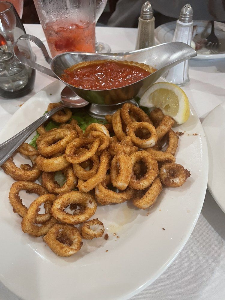 A white plate topped with fried squid rings and sauce on a table.