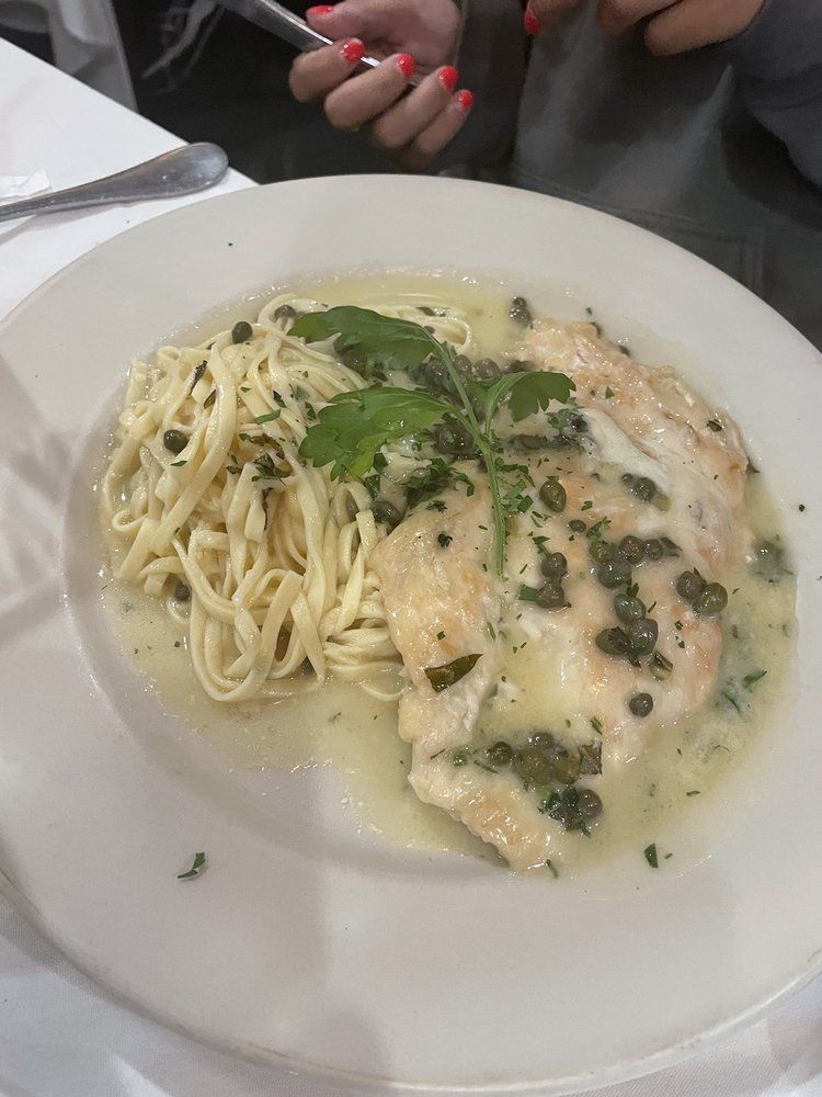 A white plate topped with noodles and chicken on a table.